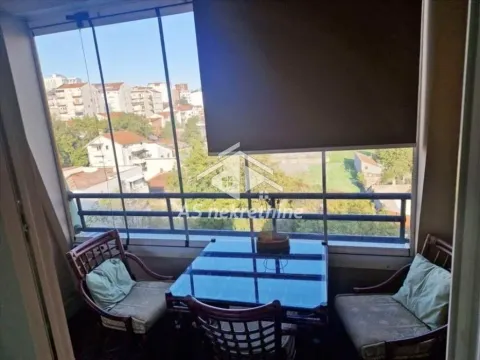 Enclosed balcony with a dining table and a city view. - image 11