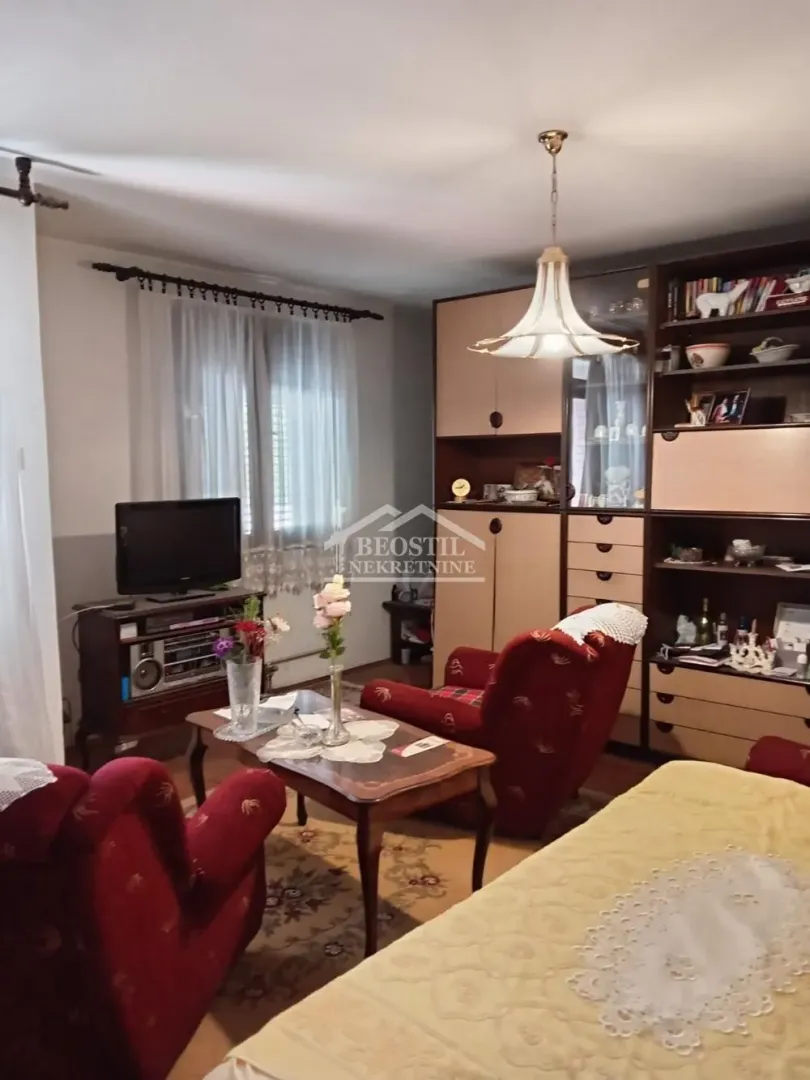 Dnevna soba sa garniturom, velikim regalom i televizorom.