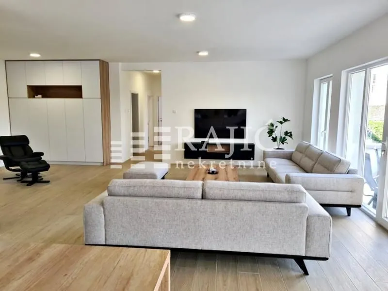 Spacious and bright living room with seating set and TV.
