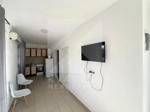 Living room with a wall-mounted TV and a kitchen in the background. - image 3