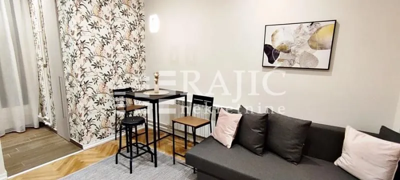 Living room with a sofa, dining table, and decorative wallpaper.