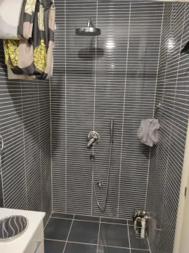 A shower cabin with grey tiles and a modern shower fixture. - image 17