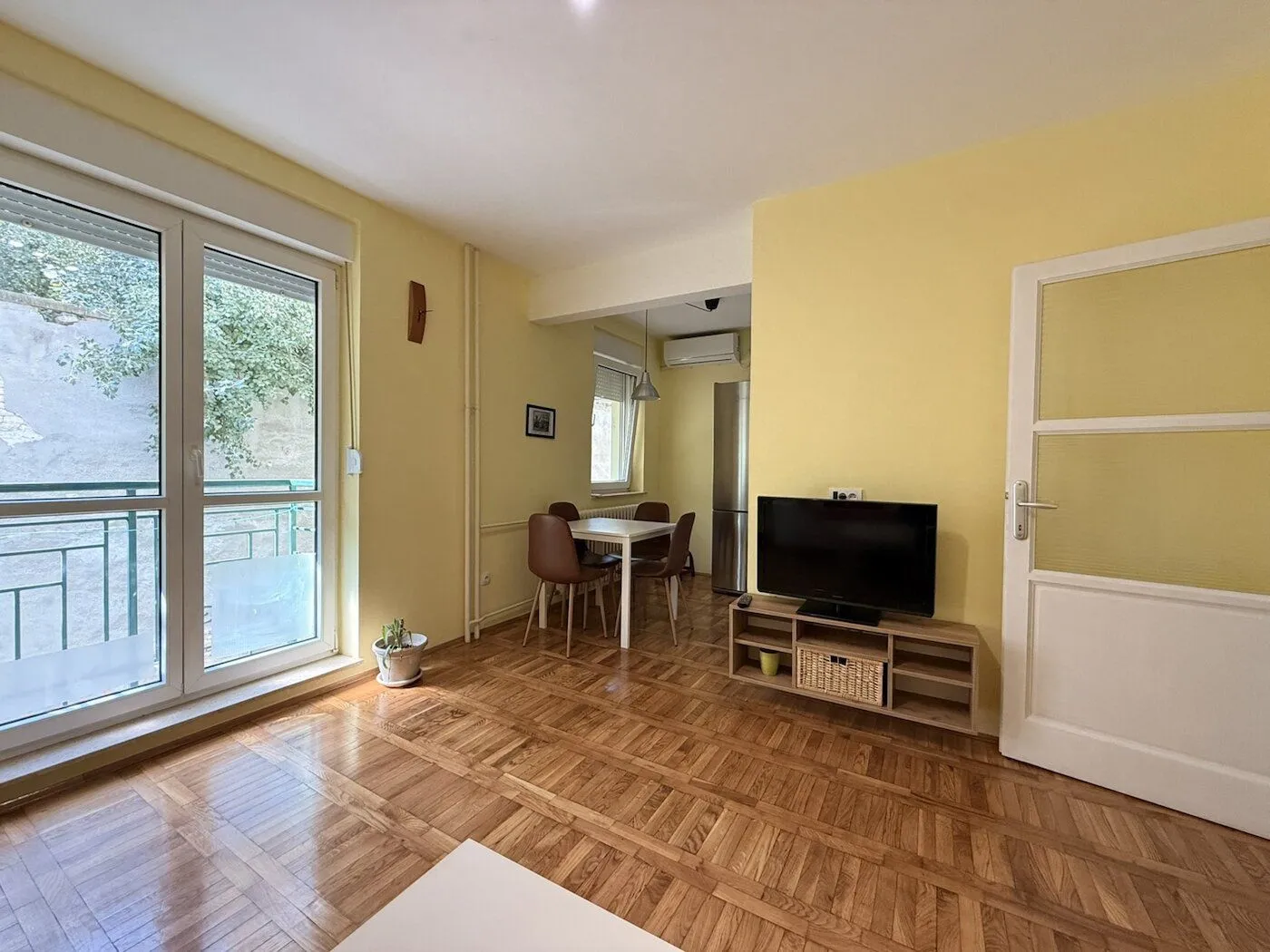 Living room with a TV unit and a dining area in the background.