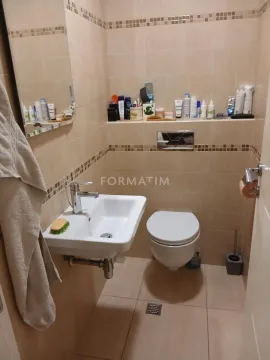 Manje kupatilo obloženo bež pločicama sa umivaonikom i šoljom. - image 4
