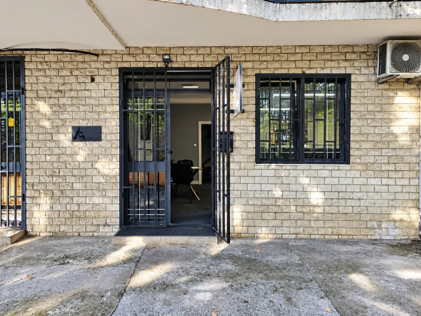 View of the entrance and facade of the building with security grills on the door and window.