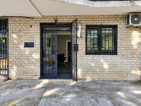 View of the entrance and facade of the building with security grills on the door and window. - image 11