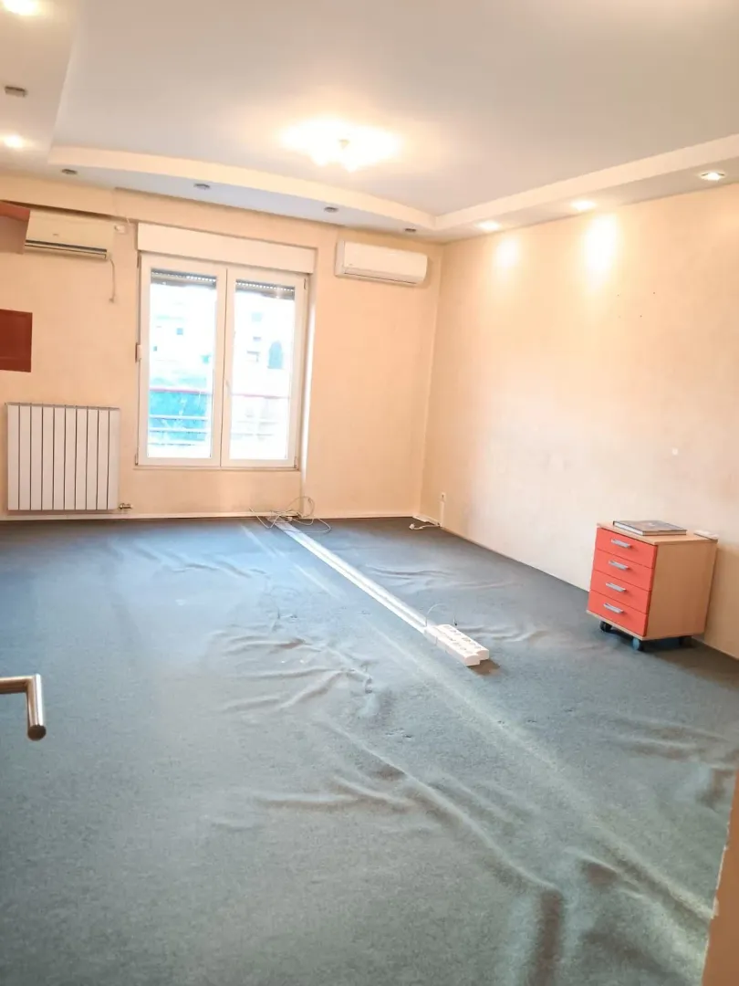Empty room with a window, air conditioner, and carpet.
