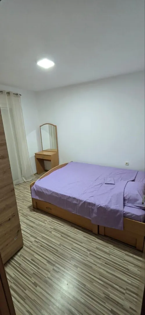 Bedroom with a double bed, wooden wardrobe, and a dressing table with a mirror.