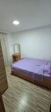Bedroom with a double bed, wooden wardrobe, and a dressing table with a mirror. - image 7