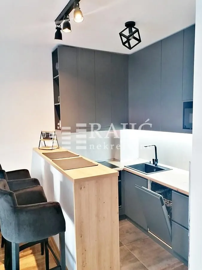 Modern kitchen with a bar counter and grey cabinets.