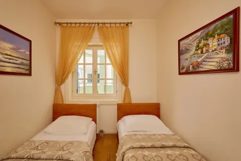 Manja spavaća soba sa dva odvojena kreveta, prozorom i slikama na zidovima. - image 13