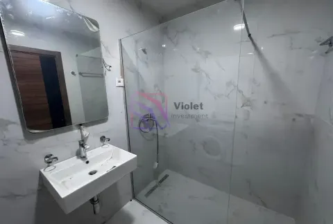 Modern bathroom with a washbasin, mirror, and a walk-in shower with a glass partition. - image 8