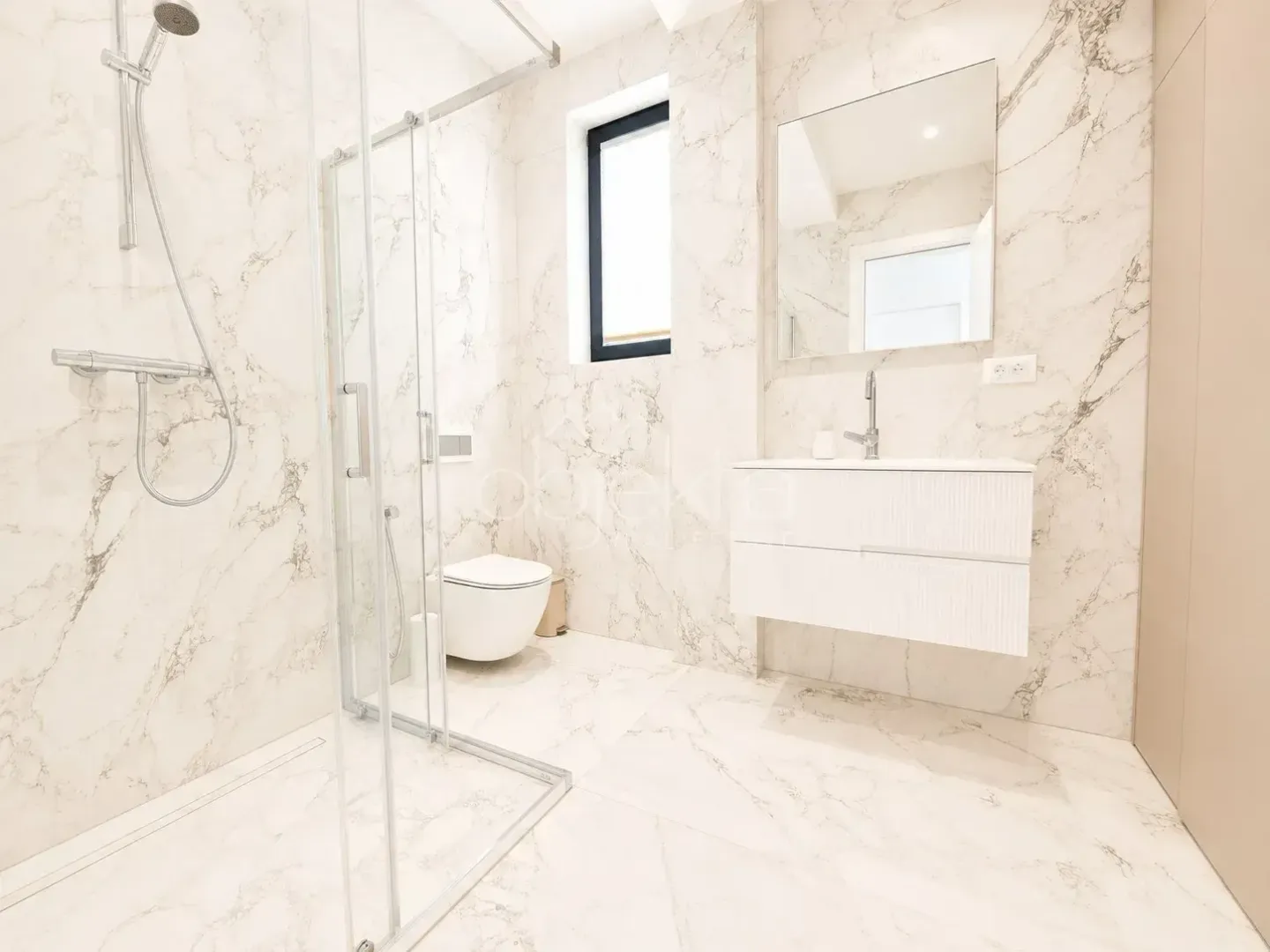 Modern marble-tiled bathroom featuring a walk-in shower and a vanity unit.