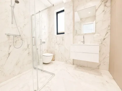Modern marble-tiled bathroom featuring a walk-in shower and a vanity unit. - image 10