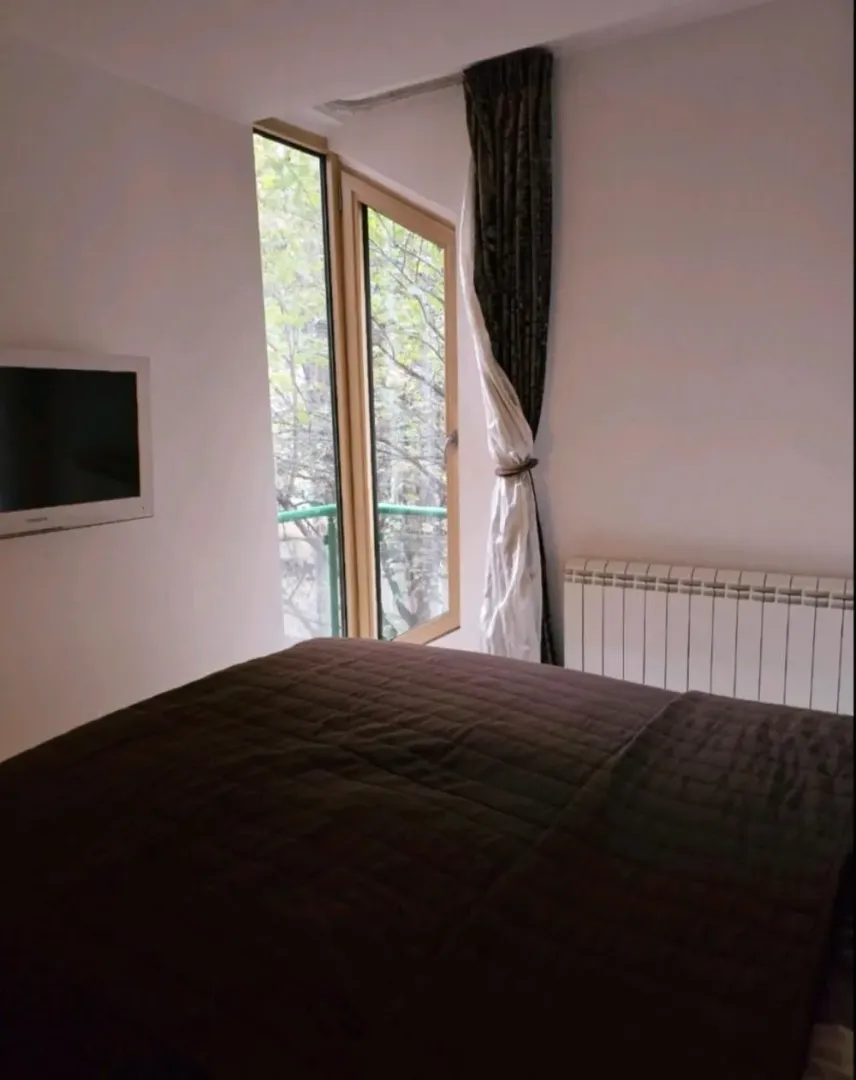 Bedroom with a double bed, wall-mounted TV, and balcony access.