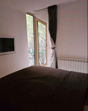 Bedroom with a double bed, wall-mounted TV, and balcony access. - image 7