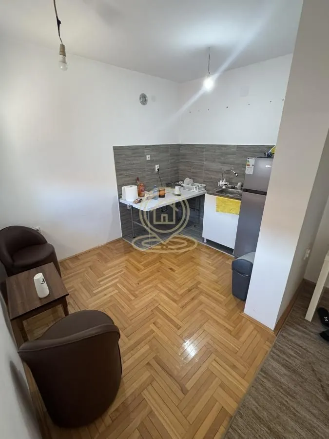 Manja kuhinja sa sudoperom, frižiderom i prostorom za sedenje sa foteljama.