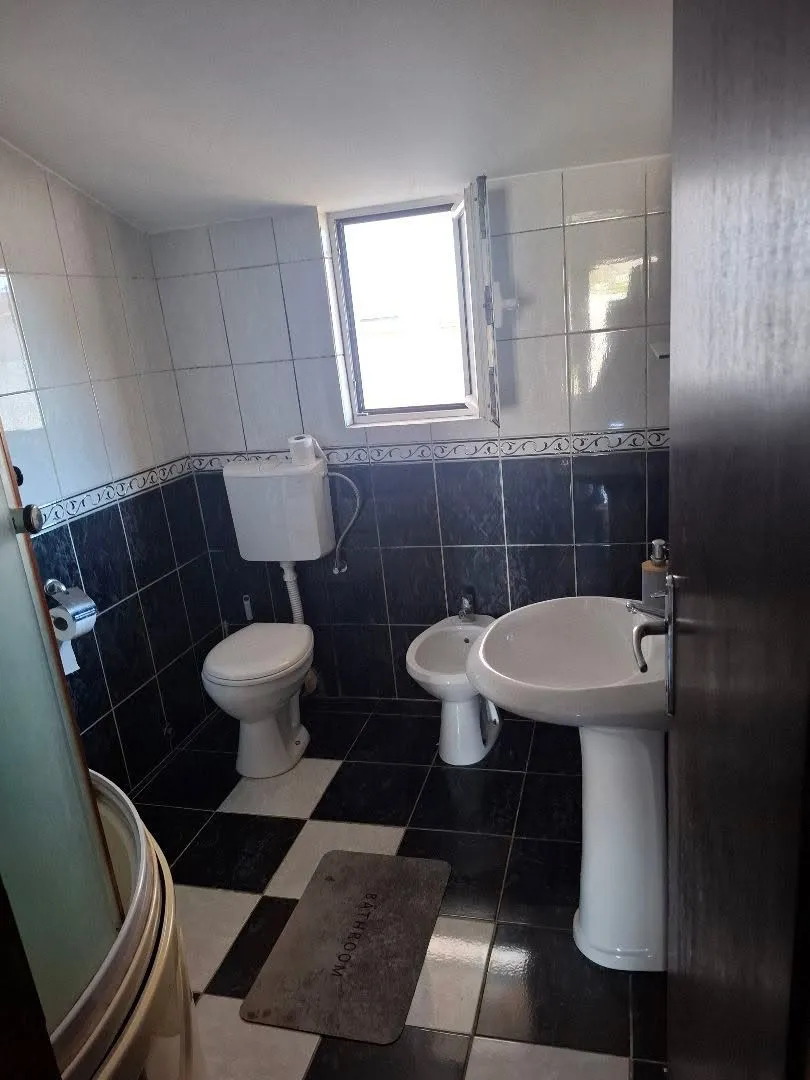Compact bathroom with white and dark tiles, sink, toilet, and bidet.