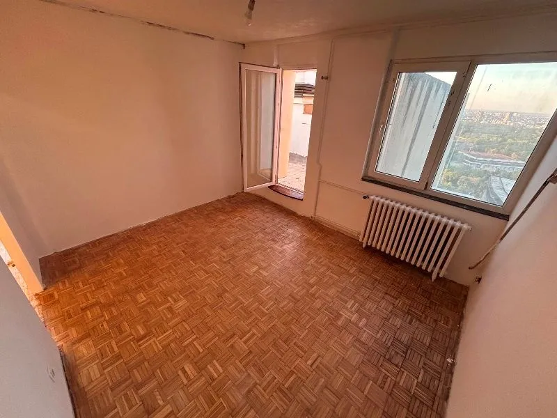 Prazna prostorija sa parketom na podu i izlazom na terasu.