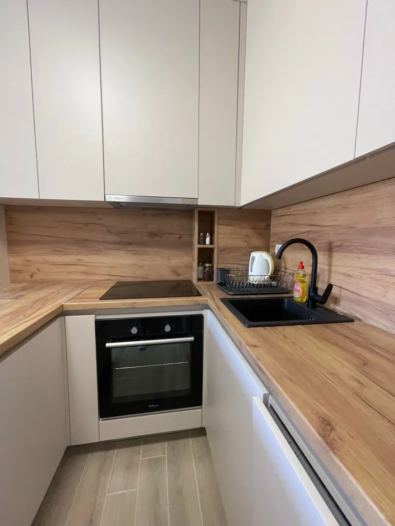 Kitchen with fitted cabinets, wood-look countertop, and a sink.
