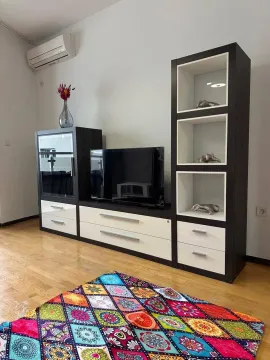 Dnevna soba sa TV komodom i šarenim tepihom. - image 11