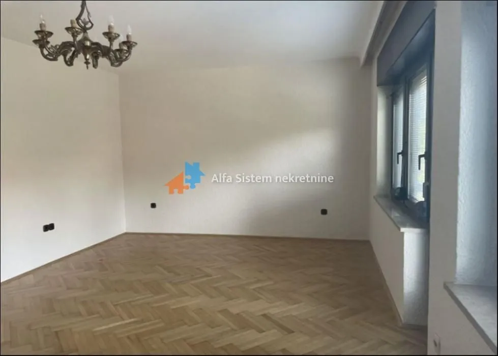 Empty room with parquet flooring and a chandelier on the ceiling.