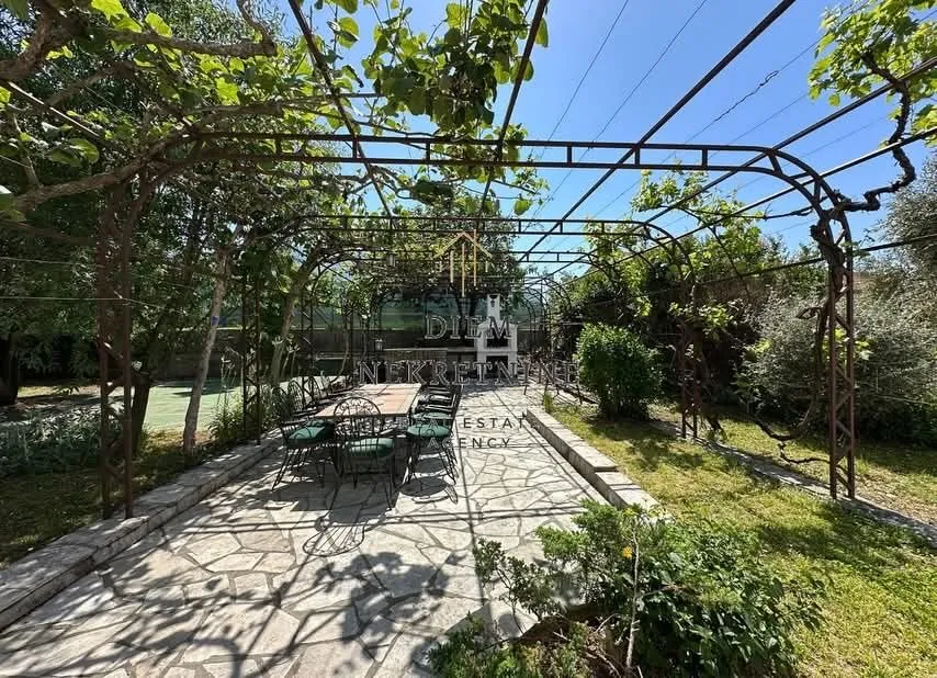 Covered patio with a dining table in a green courtyard.