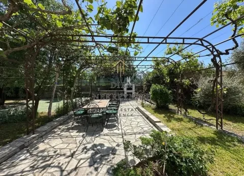 Covered patio with a dining table in a green courtyard. - image 12