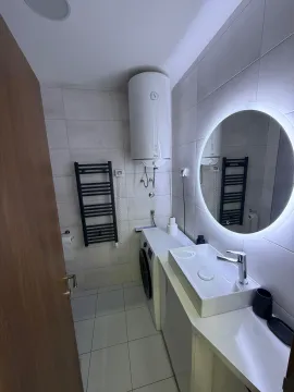 Modernly equipped bathroom with a washbasin, backlit mirror, and a washing machine. - image 11