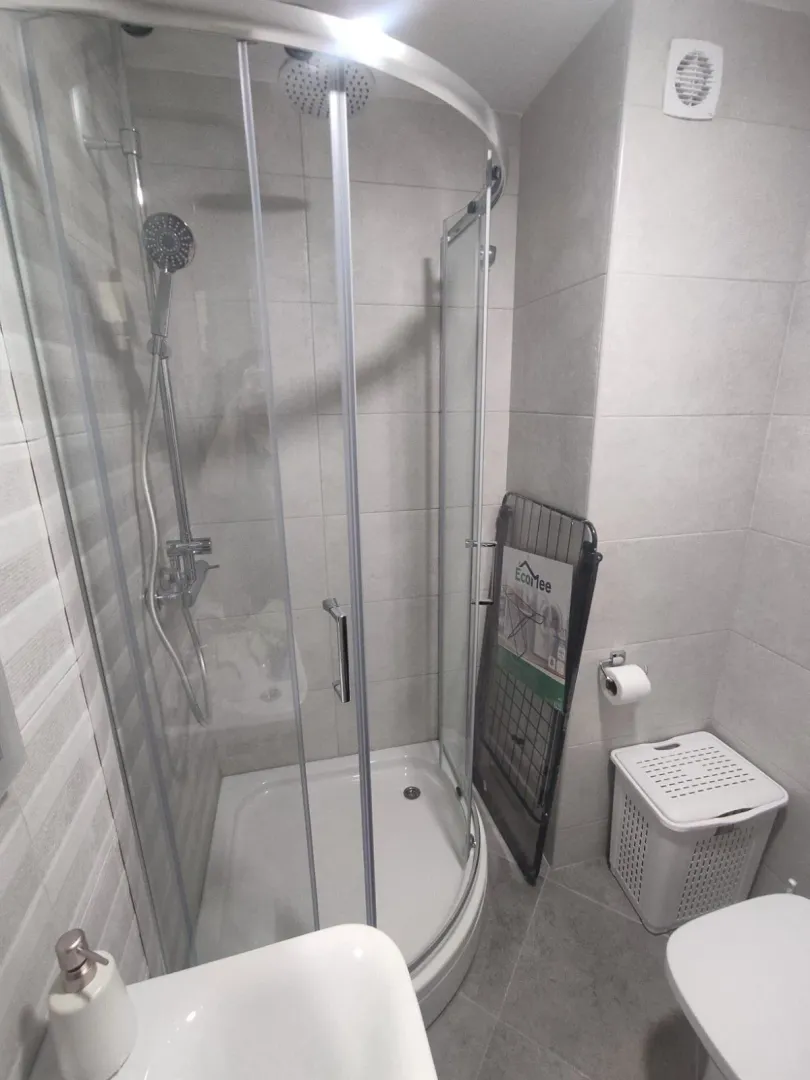 Bright bathroom with a semi-circular shower cabin.
