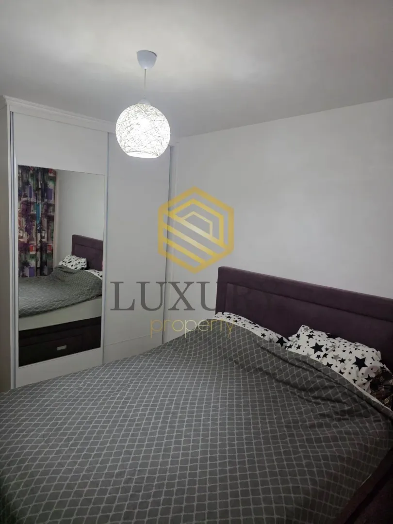 Furnished bedroom with a double bed and a built-in wardrobe with a mirror.