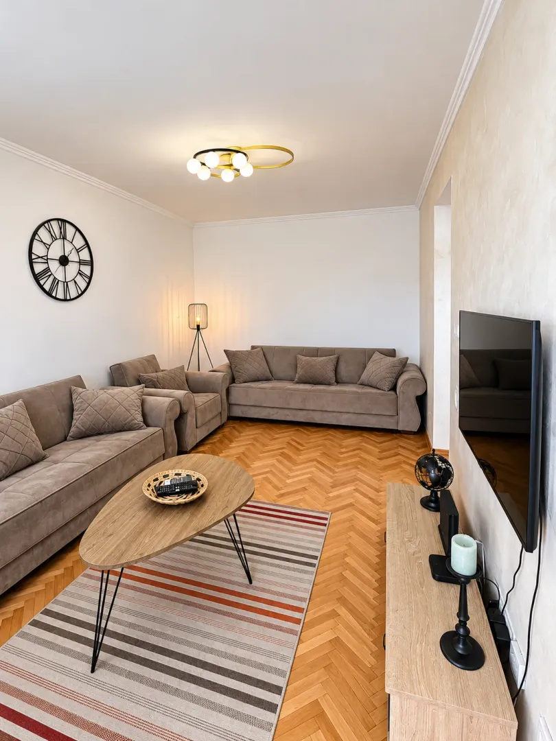 Living room with a sofa set, wooden coffee table, television, and parquet flooring.