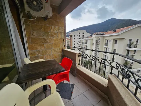 Furnished balcony with a table, chairs, and a view of surrounding buildings and hills. - image 10
