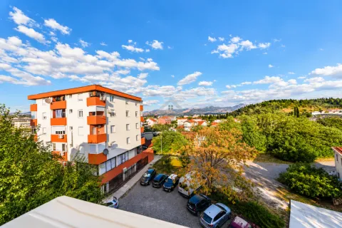 Pogled iz stana na okolne zgrade, zelenilo i planine. - image 8