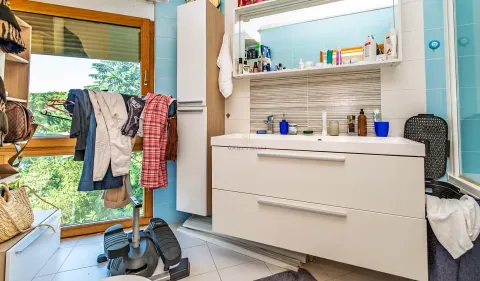 Kupatilo sa umivaonikom, ogledalom i bijelim namještajem pored prozora. - image 11