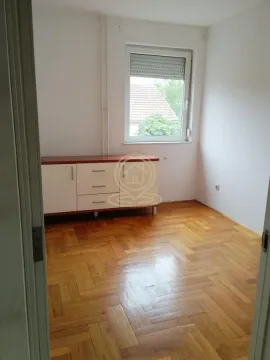 Prazna soba sa parketom i komodom ispod prozora. - image 12