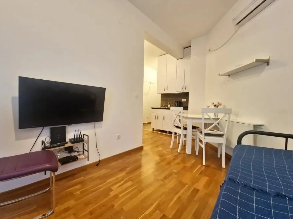 Dnevna soba sa TV-om i pogledom na trpezariju i kuhinju.