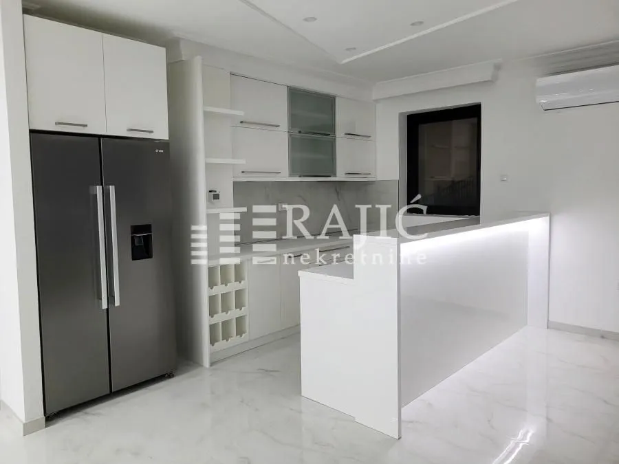 Modern white kitchen with a bar counter and built-in refrigerator.