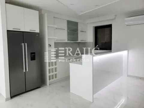 Modern white kitchen with a bar counter and built-in refrigerator. - image 5