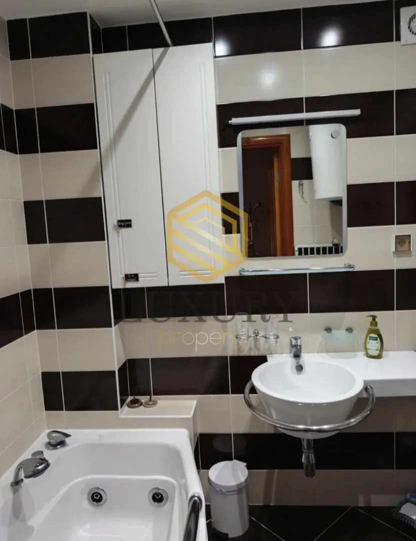 Manje kupatilo sa umivaonikom, kadom i ormarićem.