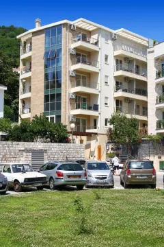Exterior view of an apartment building with parking in the foreground. - image 12
