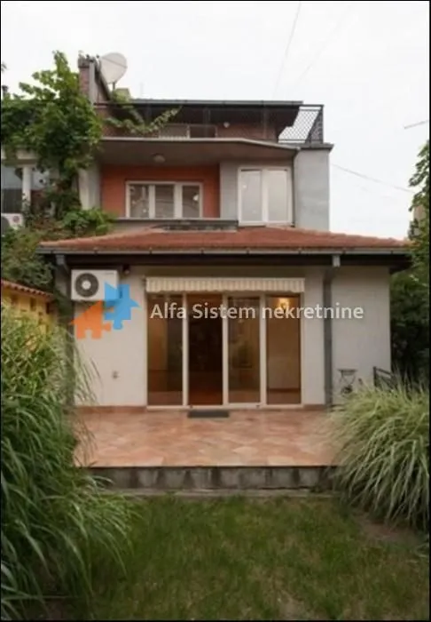 Pogled na dvorišnu stranu kuće sa terasom i zelenilom.