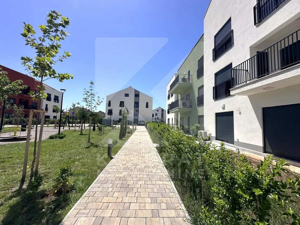 Paved walkway with landscaped courtyard and buildings in the complex.