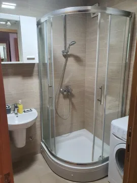 Small bathroom with a shower cabin, washbasin, and washing machine. - image 6