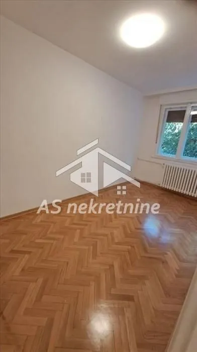 Empty room with parquet flooring and a window.