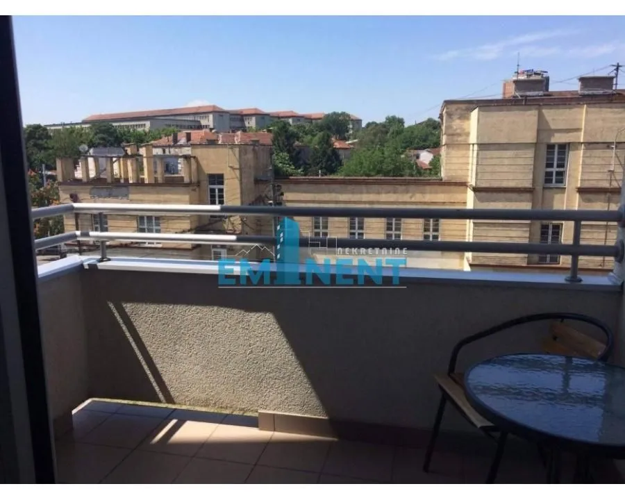 Smaller furnished balcony overlooking surrounding buildings.