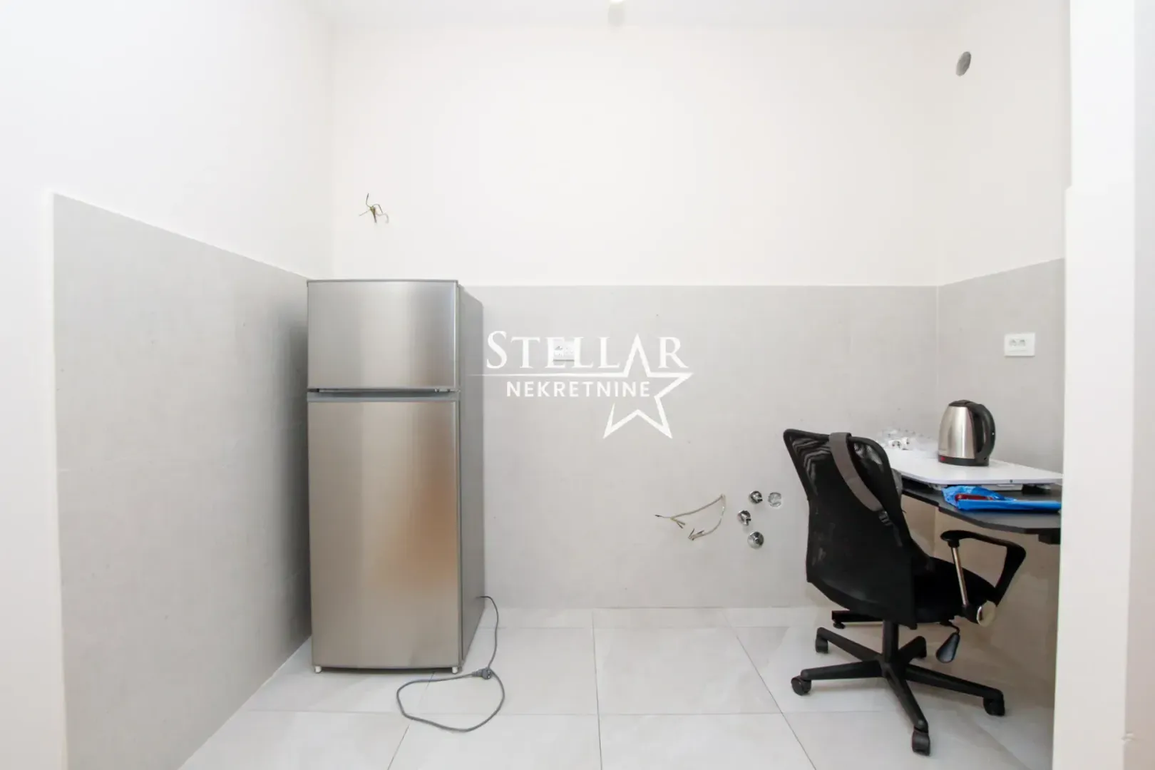 Small kitchen with a refrigerator and a desk with a chair.