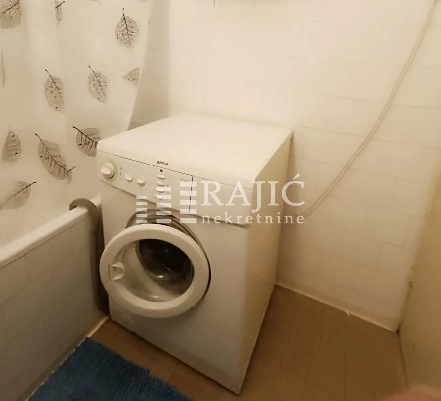 Smaller bathroom with a washing machine and bathtub.