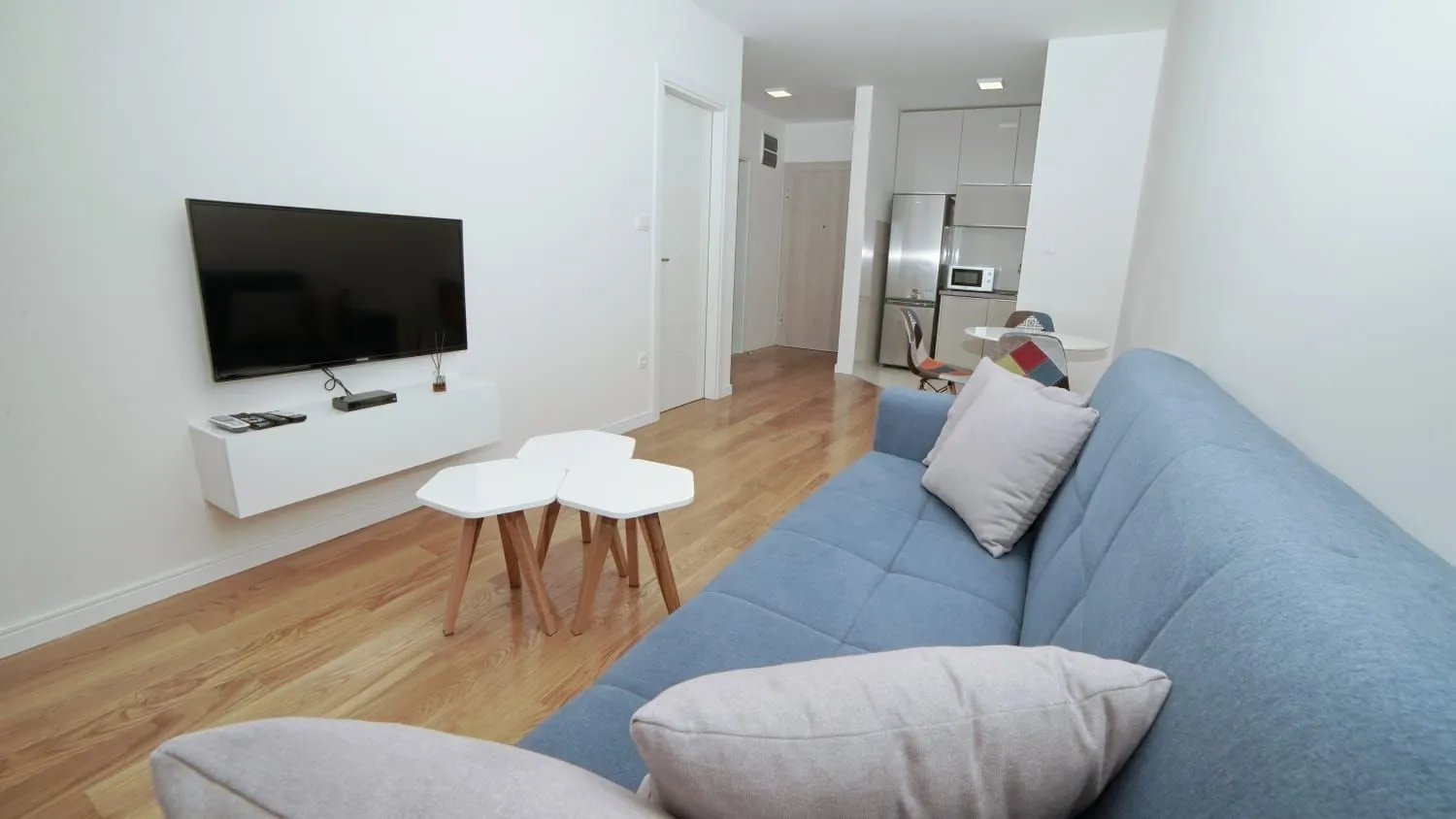 Living room with a blue sofa, TV, and view of the kitchen.