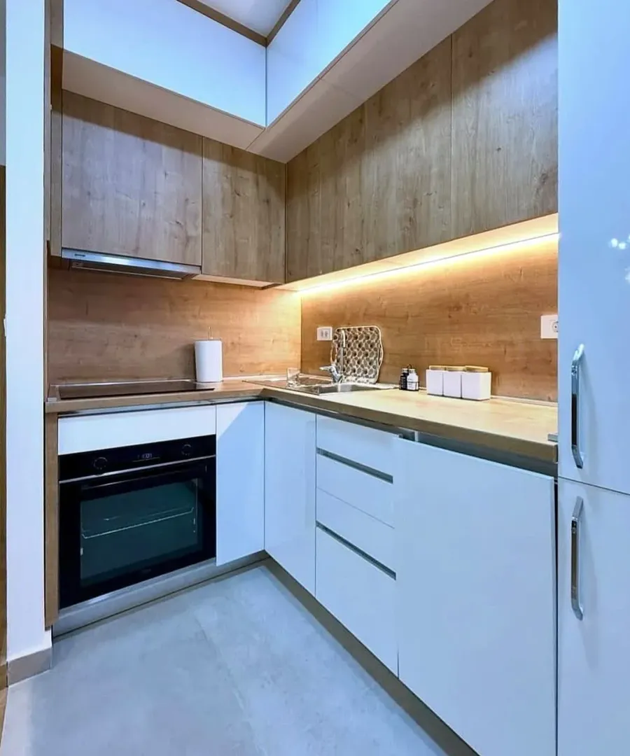 Modern kitchen with white units and wood-grain details.